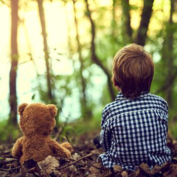 Teaching Teddy a few things about nature. a little boy sitting in the forest with his teddy bear.