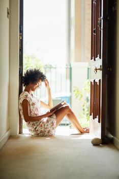 Nothing quite as relaxing as a good read. a young woman relaxing with a book at home.