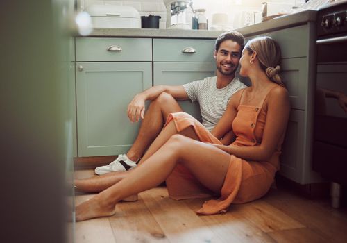 Couple, in love and on kitchen floor looking into their eyes on luxury real estate. Man, woman and communication and a conversation in a new home, house or room before breakfast with family.