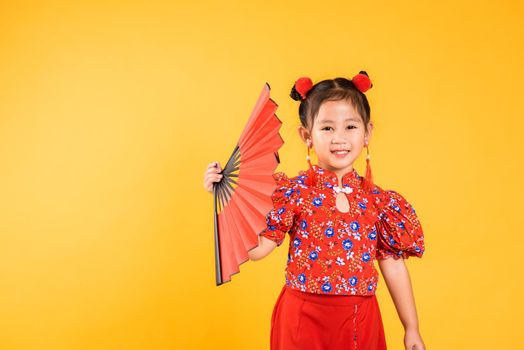 Happy Asian Chinese little girl smile wearing red cheongsam holding fan