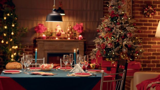 Empty traditional Christmas dinner table inside decorated living room with holiday garlands and dinnerware