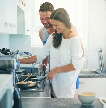 I bet you kiss as well as you cook. a happy young couple cooking together in their kitchen at home.