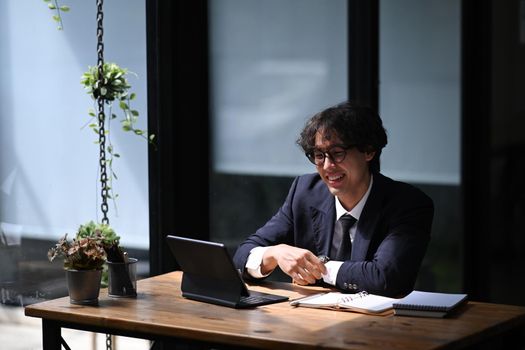 Smiling businessman watching online webinar on computer tablet.