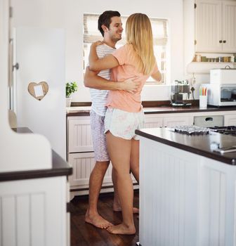 Put no restrictions on love. a happy young couple dancing in the kitchen at home.