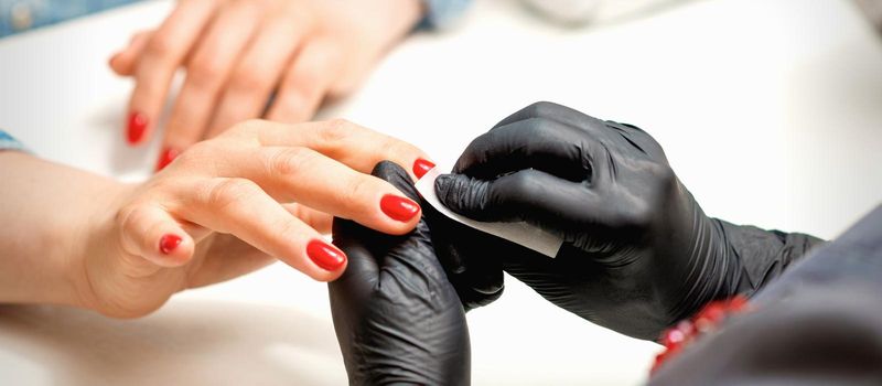 Manicurist wiping nails with napkin