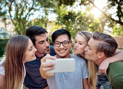 Spread the love. a young group of friends taking selfies while enjoying a few drinks outside in the summer sun.