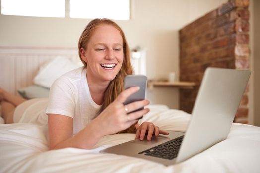 I love the connectivity I have for all my devices. a young woman laying in bed at home.