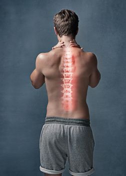 Youre only as young as your spine is flexible. Rearview shot of an unidentifiable young man with cgi indicating inflammation in his back in studio.