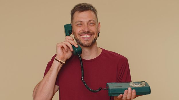 Handsome man in red t-shirt talking on wired vintage telephone of 80s says hey you call me back