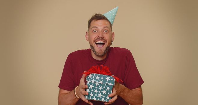 Smiling man receiving gift box, amazed satisfied with nice present, unexpected birthday surprise