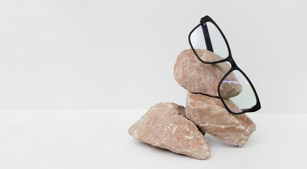 glasses on gray background wjth stone. glasses sale concept. Copy space for text. Optic store discount poster