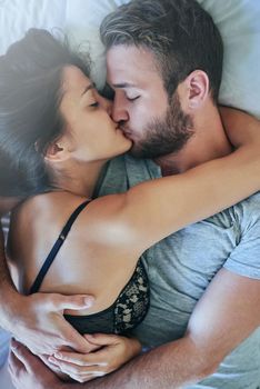 I want to cuddle all day. a loving couple sharing a kiss in bed.