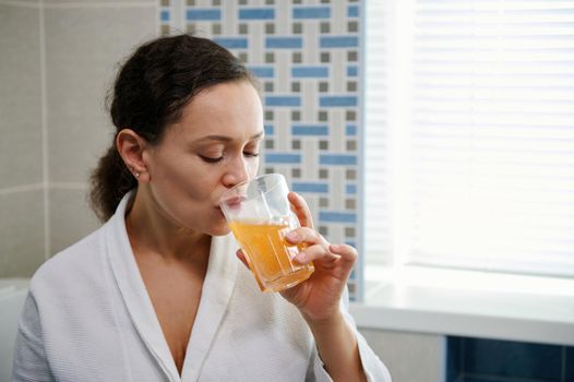 Beautiful woman drinking water with effervescent antioxidant, minerals, vitamins and nutritional supplements. Close-up