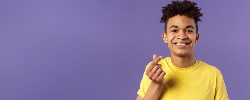 Lovely young romantic boyfriend, guy showing korean heart with fingers and smiling, like someone, being in love, show sympathy, standing purple background grinning upbeat