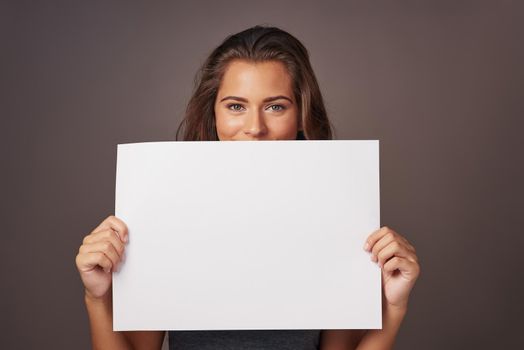 I have a statement to make. Studio shot of an attractive young woman holding a blank placard against a gray background.