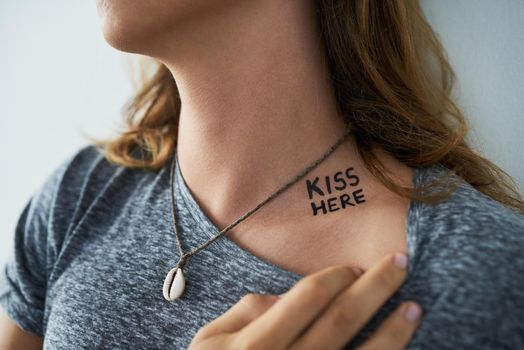 Thats the spot. a young man showing the words KISS HERE tattooed on his neck.