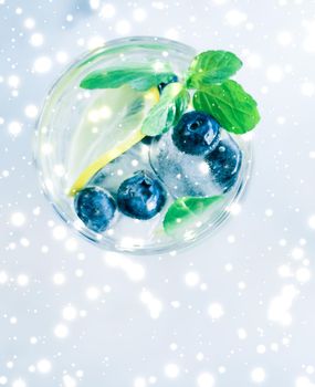 Winter holiday cocktail with ice and glowing snow on background, Christmas time menu recipe