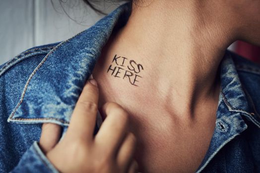 Making sensual suggestions. an unidentifiable young woman revealing a written message reading kiss here on her neck.