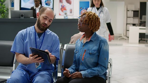Female patient and medical assistant looking at digital tablet