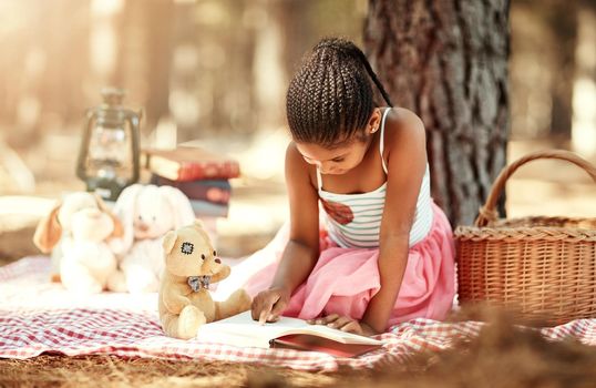 The more you read, the more youll know. a little girl reading a book with her toys in the woods.