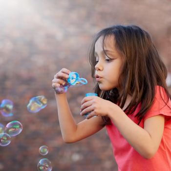 So many bubbles. a little girl blowing bubbles outside.