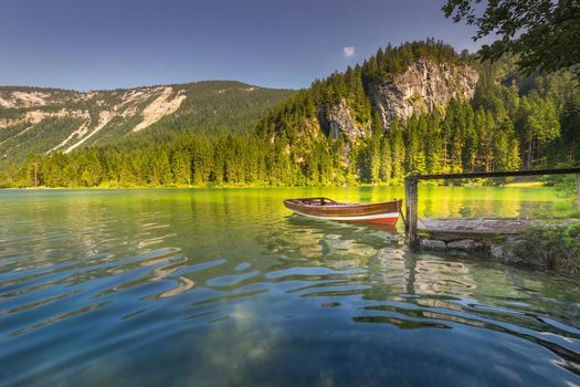 Boat anchored in Lake Tovel reflection in Trentino-Alto Adige, Dolomites, Italy