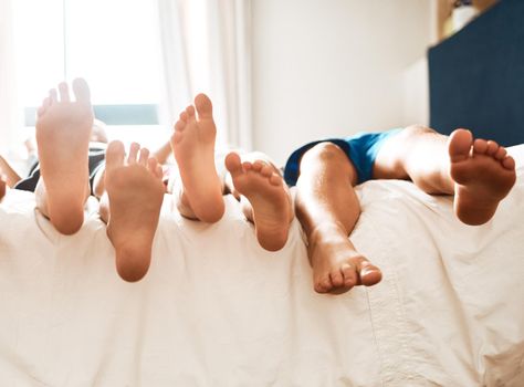 Family moments. Closeup shot of children lying barefoot on a bed at home.