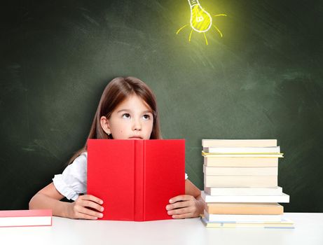 Young cute girl at chalkboard with light bulb over head