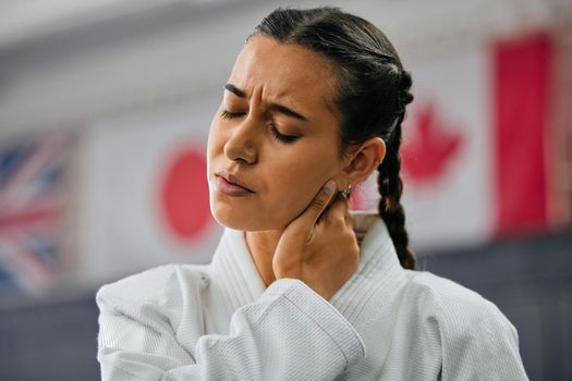 Woman karate student with bad neck pain at fitness training studio, person holding head from sport injury at health gym and muscle cramp from learning self defense at school. Painful joint accident
