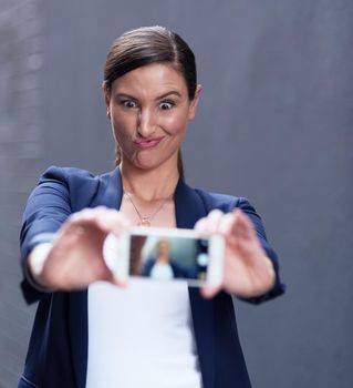 Even the CEO has a silly side. a happy businesswoman taking a fun selfie with her smartphone.