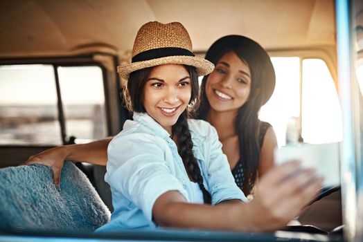 Time to make some memories. two happy friends taking selfies with a mobile phone on a roadtrip.