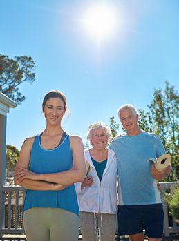 She keeps seniors fit and healthy. Portrait of a senior couple standing outside ready to do yoga with an instructor.