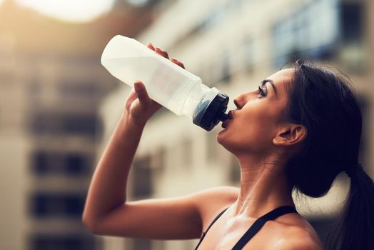Theres nothing as refreshing as water. a sporty young woman drinking water after her run.