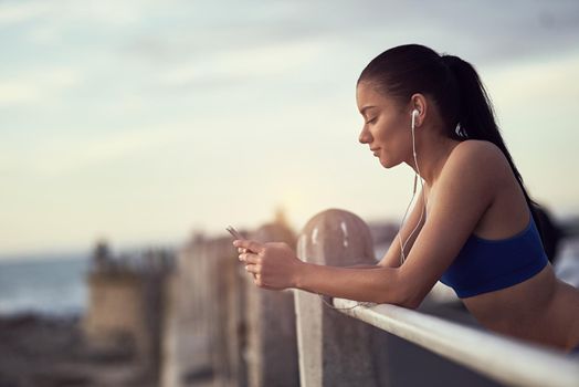 The right music makes all the difference to her workout. a fit young woman using her phone and earphones during a workout outdoors.