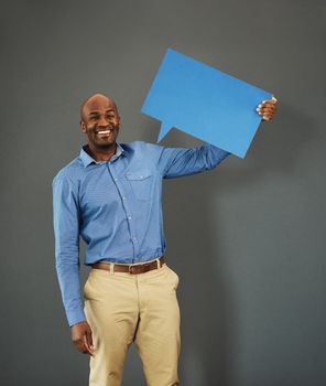 Smiling, african american male voter holding a copyspace board sign on public opinion message. Casual and positive man holding a social media speech bubble or communication icon for news poll idea