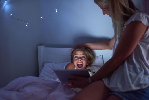 Bedtime never felt more exciting. a little girl and her mother using a digital tablet before bedtime.