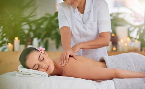 Unwind and enjoy the tranquil times. an attractive young woman enjoying a back massage at a spa.