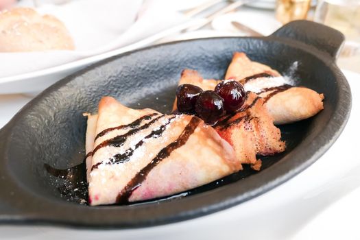 French crepes with chocolate sauce and cherries in a reastaurant in Paris, pancakes recipe