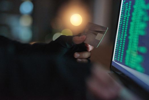 Its easier than you think for thieves to attack. an unrecognisable hacker using a laptop to hack into a credit account.