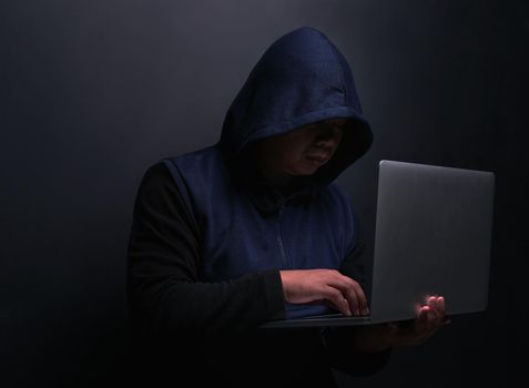 Hackers are the masters of stealth. an unrecognisable hacker using a laptop against a dark background.