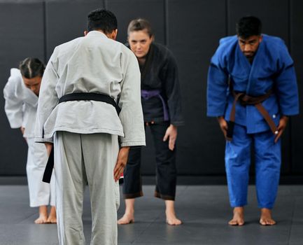 Fitness, strength and respect between karate trainer leading a class, bow and greeting martial arts student at a dojo or studio. Diverse group training and learning self defense and endurance skills