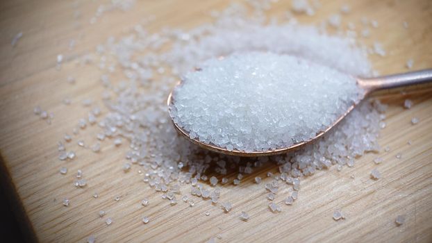 A full spoon with sugar on a wooden table