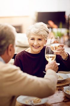 Bon appetit. an elderly couple toasting with wine glasses while they enjoy a meal at home.