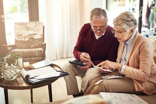 Its necessary to have a contingency plan for old age. an elderly couple working out a budget while sitting on the living room sofa.