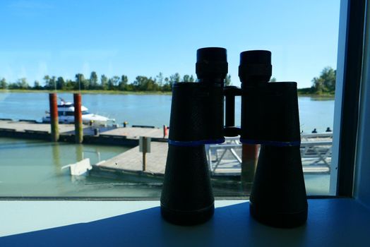 Binoculars on a window sill overlooking a dock