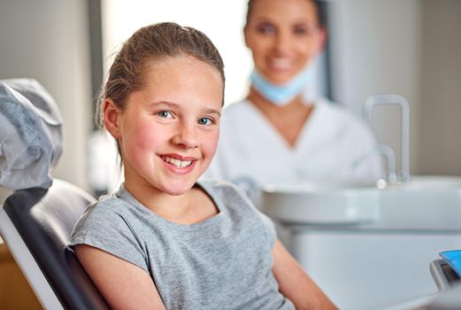 Shes in for a routine check-up. Shot of a young girl sitting in a dental chair with her dentist in the background.