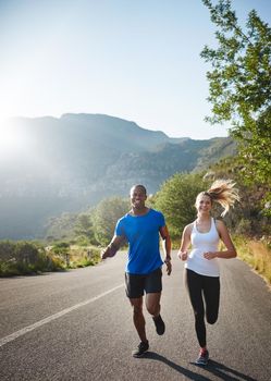 Running is a form of relaxation. a sporty couple out running on a mountain road.