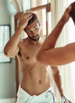 It takes hard work to look this casual. a shirtless man checking out his hair in the bathroom mirror.