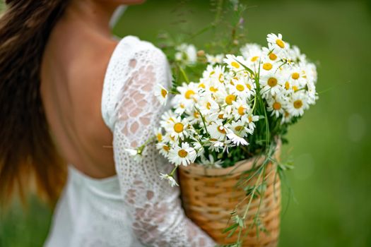 A middle-aged woman holds a large bouquet of daisies in her hands. Wildflowers for congratulations