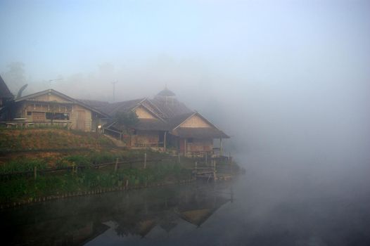 wooden house in the morning mist and the lake view in the countryside